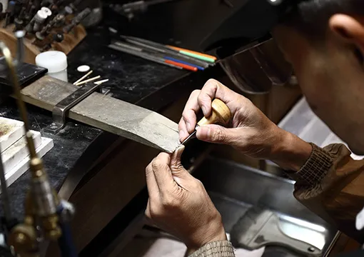 職人が指輪に石留めしている写真